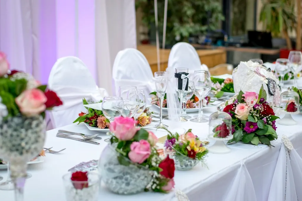 Reception tables dressed in white with blush and fuchsia centrepieces