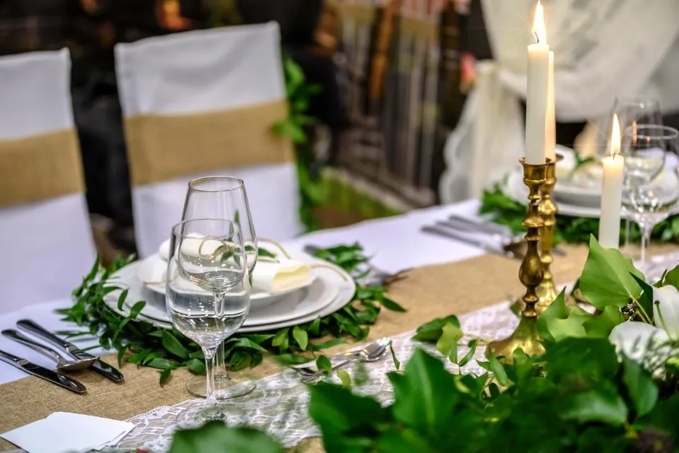 Long table with gold candlesticks, greenery runner and white china